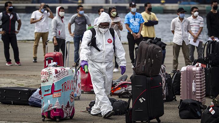 Petugas kesehatan menyemprotkan cairan disinfektan ke atas permukaan barang bawaan milik Warga Negara Indonesia (WNI)